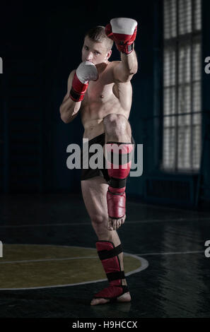 Jeune homme athlétique avec des gants de boxe et un rack Banque D'Images