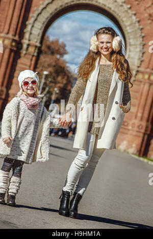 À Barcelone pour un hiver parfait. Portrait of happy trendy la mère et l'enfant debout près de Arc de Triomf à Barcelone, Espagne Banque D'Images