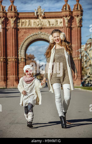À Barcelone pour un hiver parfait. Full Length portrait of smiling mother and daughter branché près de Arc de Triomf de Barcelone, Espagne randonnée pédestre Banque D'Images