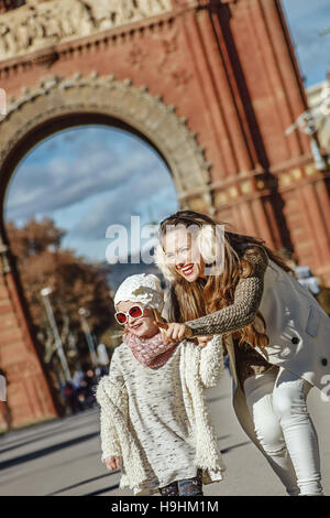 À Barcelone pour un hiver parfait. Bonne mère tendance pointant sur quelque chose à l'enfant près de Arc de Triomf à Barcelone, Espagne Banque D'Images