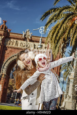 À Barcelone pour un hiver parfait. Portrait of smiling mother and daughter branché près de Arc de Triomf de Barcelone, l'Espagne ayant du plaisir Banque D'Images
