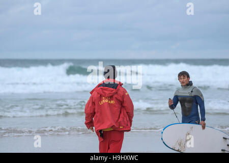 Un sauveteur RNLI parlant à un surfeur sur la plage de Fistral, Newquay, Cornwall. Banque D'Images