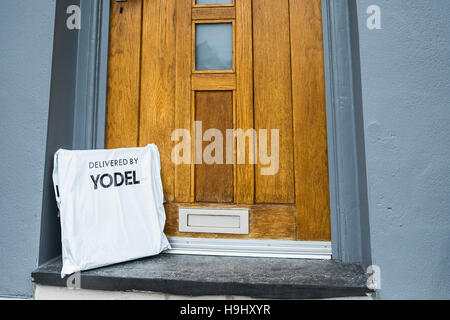 Un colis livré à une maison par yodel et à gauche sur la porte. Banque D'Images