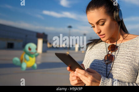 Young woman playing pokemon rendez sur une tablette Banque D'Images