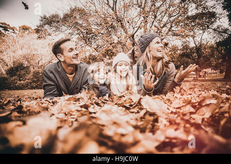 Smiling young family Jeter feuilles autour de Banque D'Images