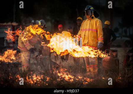 Silhouette de pompiers la lutte contre un feu faisant rage avec d'immenses flammes de bois brûlant Banque D'Images
