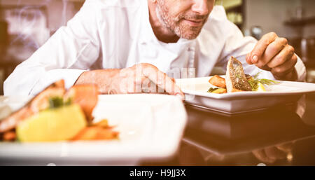 Concentrés male chef garniture food in kitchen Banque D'Images