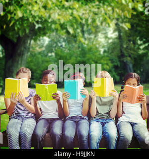 Image composite de la lecture de livres pour enfants au parc Banque D'Images