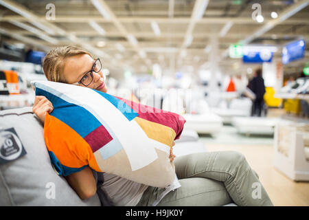 Jolie jeune femme choisir le bon mobilier pour son appartement dans un magasin d'accessoires de maison moderne aux tons de couleurs (DOF) peu profond de l'image ; Banque D'Images