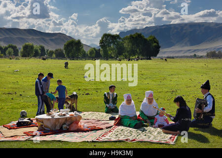 Pique-nique en famille en vêtements traditionnels chantant en pâturages retournerais sans hésiter sur la rivière Chilik Kazakhstan Banque D'Images