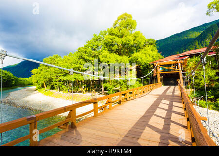 La sinueuse rivière Azusa turquoise sous le pont incliné de l'emblématique pont Kappa Bashi que sun sur la montagne dans Kamikochi Banque D'Images