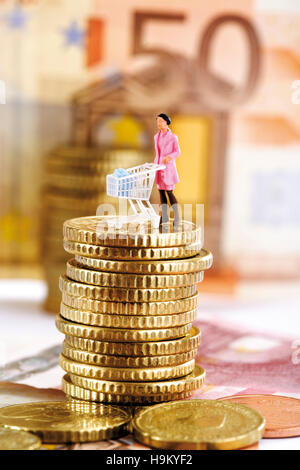 Figurine d'une femme poussant un chariot sur une pile de pièces Banque D'Images