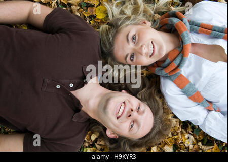 Young couple lying in autumnal leaves Banque D'Images