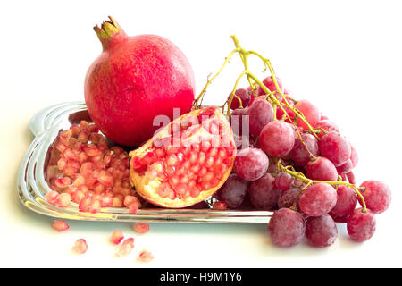 Les raisins rouges frais et de grenadiers Plaque sur fond blanc,concept santé Banque D'Images