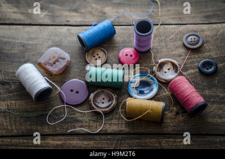 Bobines avec des threads et des boutons sur la vieille table en bois, l'arrière-plan Banque D'Images