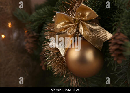 Golden Christmas ball. Libre de l'or avec bow babiole accrochée à l'arbre de Noël décoré. Banque D'Images