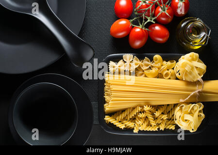 Collection pâtes crues et les tomates sur le tableau noir Banque D'Images