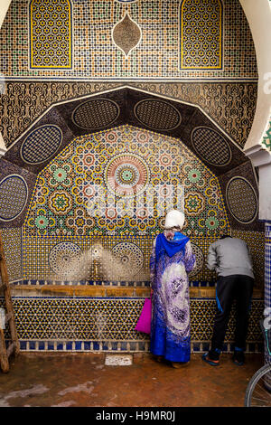 La population locale à la collecte de l'eau d'une fontaine d'eau publique dans la médina, Fès el Bali, FES, Maroc Banque D'Images