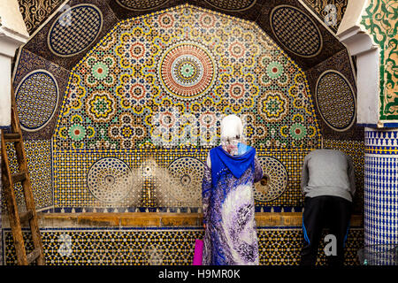 La population locale à la collecte de l'eau d'une fontaine d'eau publique dans la médina, Fès el Bali, FES, Maroc Banque D'Images