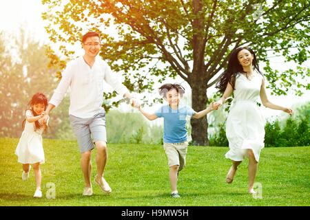 Des familles heureuses courir sur l'herbe Banque D'Images