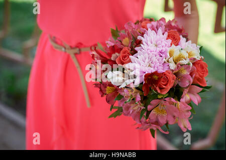 Demoiselles dans une robe rouge avec bouquet de mariage Banque D'Images