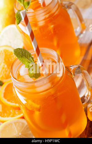 La limonade à l'orange, la glace et la menthe dans un bocal de verre vertical de macro. Banque D'Images