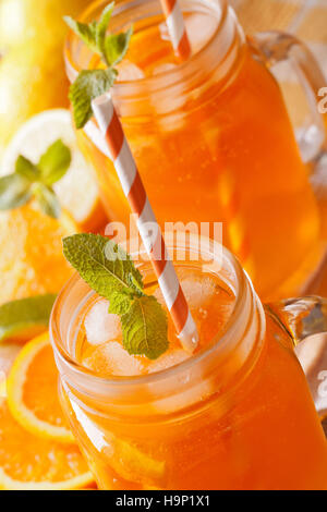 Cocktail rafraîchissant avec des oranges, des citrons, de la glace et la menthe dans un bocal de verre vertical de macro. Banque D'Images