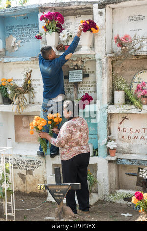 Une famille mexicaine prend des fleurs à la tombe d'un parent à l'Nuestra Se-ora de Guadalupe cemetery pendant le jour de la fête des morts le 1 novembre, 2016 à San Miguel de Allende, Guanajuato, Mexique. La semaine de célébration est un moment où les Mexicains bienvenue les morts à la terre pour une visite et célébrer la vie. Banque D'Images