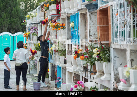 Une famille mexicaine prend des fleurs à la tombe d'un parent à l'Nuestra Se-ora de Guadalupe cemetery pendant le jour de la fête des morts le 1 novembre, 2016 à San Miguel de Allende, Guanajuato, Mexique. La semaine de célébration est un moment où les Mexicains bienvenue les morts à la terre pour une visite et célébrer la vie. Banque D'Images