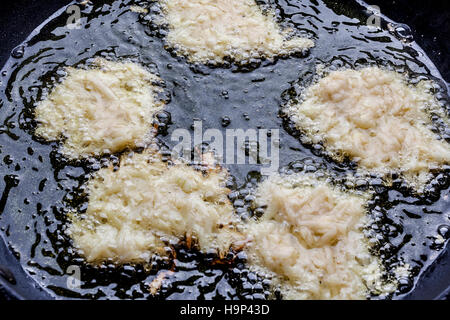 Latkes friture avec les matières premières vers le haut dans une profonde huile sur pan d'en haut Banque D'Images