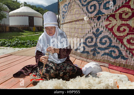 Kazakh femme âgée dans la robe nomade locale tournant la laine. Banque D'Images