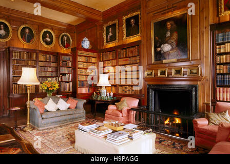 Vue de la chambre de la bibliothèque à Antony House montrant cheminée, bibliothèque, chaises et des lambris en pin. Banque D'Images