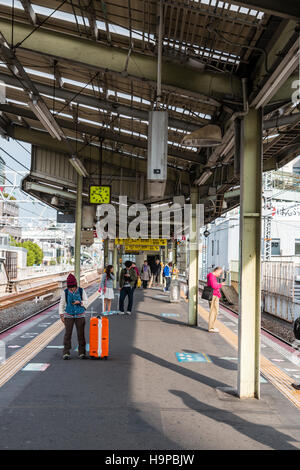 Japon, Osaka, JR Shin-imamiya station sur l'Osaka Loop line. Afficher le long de la plate-forme avec des gens qui attendent pour le prochain train. Banque D'Images