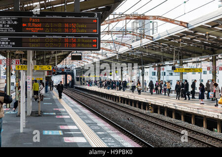 Japon, Osaka, JR Shin-imamiya station sur l'Osaka Loop line. Afficher le long de la plate-forme avec des gens qui attendent pour le prochain train. Banque D'Images