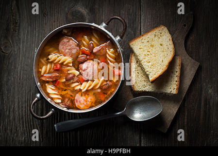 Ragoût de haricots frais avec de la saucisse et des pâtes sur fond de bois Banque D'Images