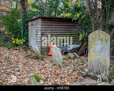 Ancien hangar en bois au coin de cimetière parmi des pierres tombales Banque D'Images