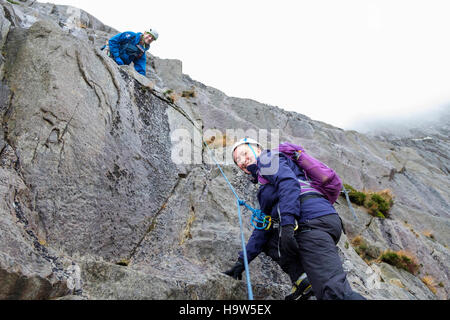 Un moniteur d'escalade de montagne d'apprentissage enseignement novices pour coder sur des rochers avec une corde pour la protection dans le pays de Galles Snowdonia Idwal Royaume-uni Grande-Bretagne Banque D'Images