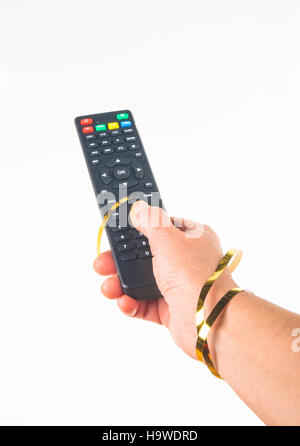 Main tenant une télécommande dans un ruban d'or de fête sur fond blanc Banque D'Images
