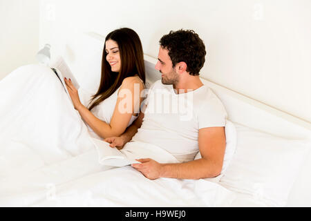 Charmante jeune couple reading books dans le lit Banque D'Images