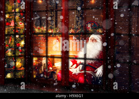 Du vrai Père Noël. Père Noël assis dans le salon près de l'arbre de Noël. Vue de l'extérieur par la fenêtre. Banque D'Images