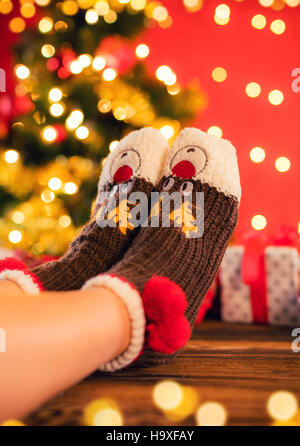 Détail de femme pieds de chaussettes de laine, le flou d'arrière-plan sur l'arbre de Noël Banque D'Images