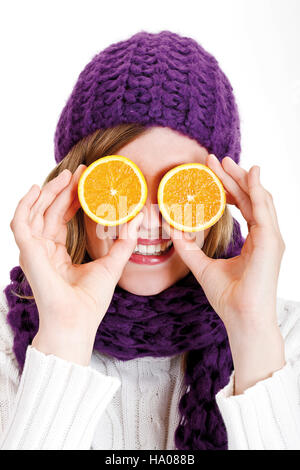 Jeune femme portant un foulard et bonnet de pourpre tenant les moitiés d'orange devant ses yeux Banque D'Images