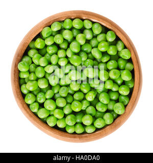 Pois crus dans bol en bois. Petites graines sphériques vert de la gousse fruit Pisum sativum, une légumineuse comestible. Macro photo alimentaire isolé Banque D'Images