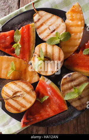 Fruits grillés : pastèque, melon, pomme, poire sur une plaque verticale. macro vue du dessus Banque D'Images