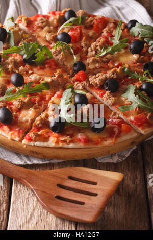 Des pizzas au thon, olives et la roquette close-up sur la table verticale. Banque D'Images