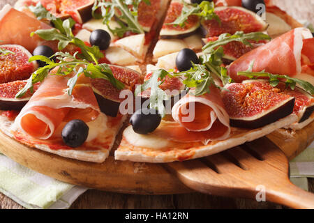 Pizza aux figues, jambon et mozzarella macro sur une planche de bois horizontal. Banque D'Images