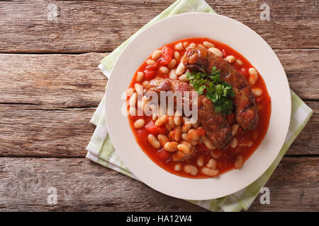 Saucisses grillées avec des haricots à la sauce tomate dans une assiette sur la table horizontale vue du dessus. Banque D'Images