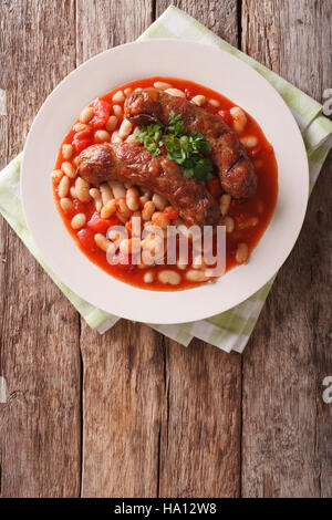 Saucisses grillées avec des haricots à la sauce tomate dans une assiette sur la table. vertical Vue de dessus Banque D'Images