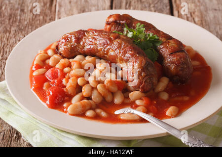 Saucisses aux haricots à la sauce tomate dans une assiette sur la table horizontale. Banque D'Images