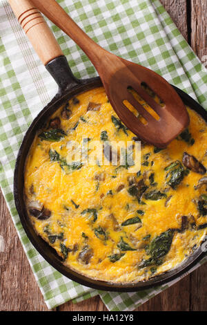 Délicieux omelette aux épinards, fromage cheddar et les champignons dans une casserole sur la table. Vue verticale d'en haut Banque D'Images